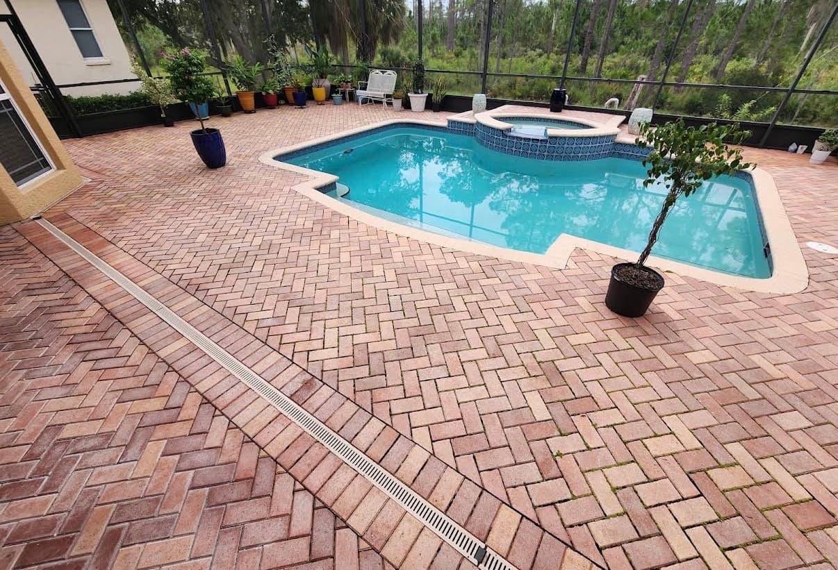 A herringbone paver pool deck inside a screened pool cage