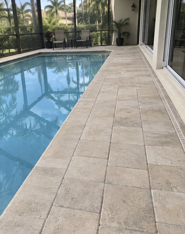 A pool deck and lanai beside a modern home at sunset (after)