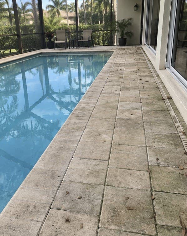 A pool deck and lanai beside a modern home at sunset (before)
